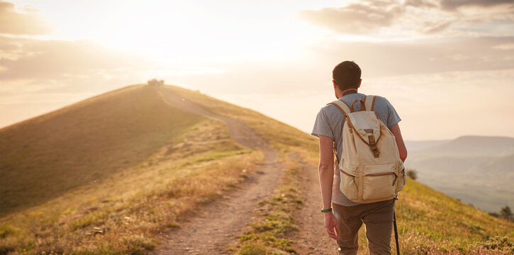 Young man travels alone walking on trail and enjoying on view of mountains and sea landscape at sunset , the lifestyle concept of traveling outdoors.