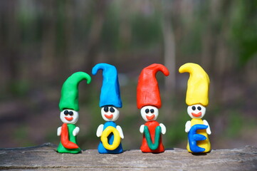 Naklejka premium Figures of colorful dwarfs on a colored background. They hold letters in their hands. The inscription is love.