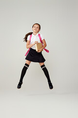 cute happy schoolgirl jumping up with backpack