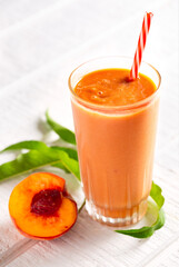 Fresh peach smoothie on a light wooden surface with copy space