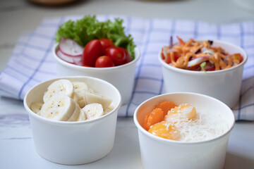 Take away healthy food in foil boxes on marble table.