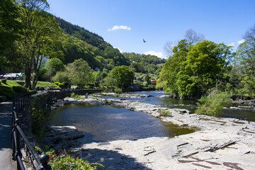 Llangollen - Wales - May 11 2019 :  Beautiful landscape. Summer scene of the river Dee flowing over rocks. Wooded hillsides and clear blue sky. Landscape aspect.  Copy space.