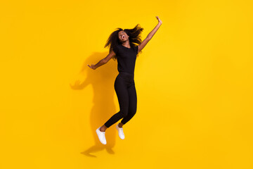 Fototapeta na wymiar Full size photo of impressed cool young lady jump wear black outfit isolated on yellow color background