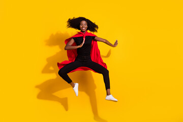 Fototapeta na wymiar Full body photo of happy nice dark skin woman jump up wear cape super hero isolated on yellow color background