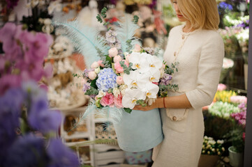 beautiful flower arrangement in box of orchids hydrangea and different flowers in hands of blonde woman