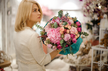 handsome blonde woman with flower bouquet wrapped in turquoise wrapping paper in her hand