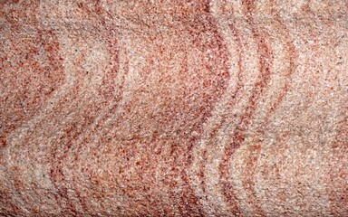 Textured Sandstone with Curving Lines in Red and Pink on a Rough Flat Surface