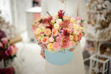 close-up of beautiful floral arrangement of rose orchids and carnations in box in the hands of woman