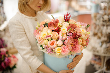close-up floral arrangement of rose orchids and carnations in box in the hands of woman