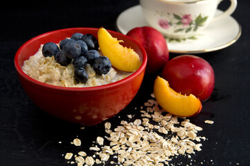 Oatmeal with Blueberries and Nectarines in a Red Bowl with Dark Background
