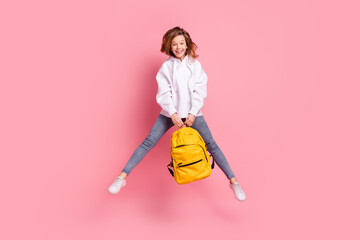 Full length body size girl jumping up keeping schoolbag happy cheerful isolated pastel pink color background