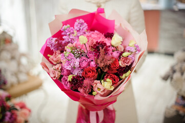 Close-up of amazing bouquet of various fresh flowers wrapped in bright pink paper