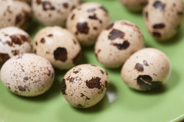 Fototapeta premium Quail eggs on a green ceramic plate