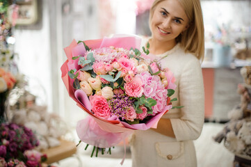 smiling woman holds great bouquet of pink chrysanthemum hydrangea and roses