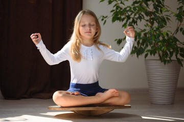 A child balancing on a balance board in a lotus position. Concept - pupil mental health