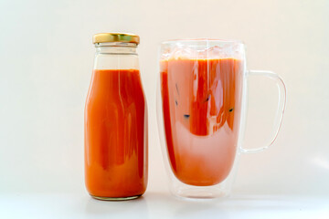 Orange Thai milk tea put in a bottle and put a glass with ice on the back with a white background