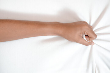 Young woman in bed clutching tightly her hand Bed pulling and grab white bed sheet.