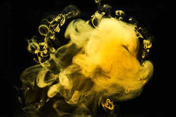 Abstract liquid art, yellow smoke bomb on black background, amber color acrylic paints under water