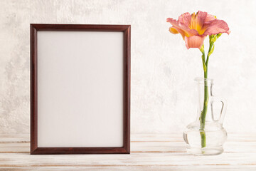 Wooden frame with purple day-lily flowers in glass vase on gray concrete background. side view, copy space.