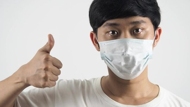 Asian man wearing protect mask and thumb up for giving encourage portrait white isolated head shot
