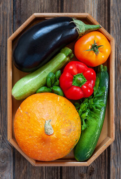 Close-up photo of fresh farm organic vegetables and greenery. Top view on wooden background