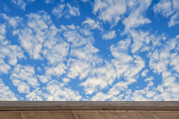 blue sky with white clouds over wooden wall