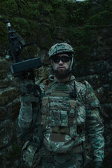 Fototapeta premium Portrait of airsoft player in professional equipment with machine gun in the forest. Soldier with weapons at war