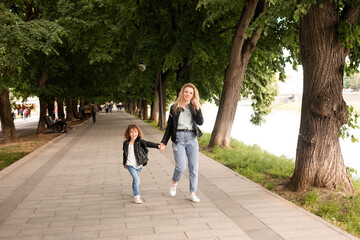 Obraz premium The mom and little girl walk around the city are holding hands