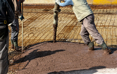 Builders works on the construction site: pouring brown concrete for foundation