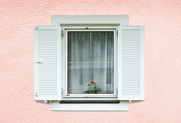 Windows with white shutters on light pink facade