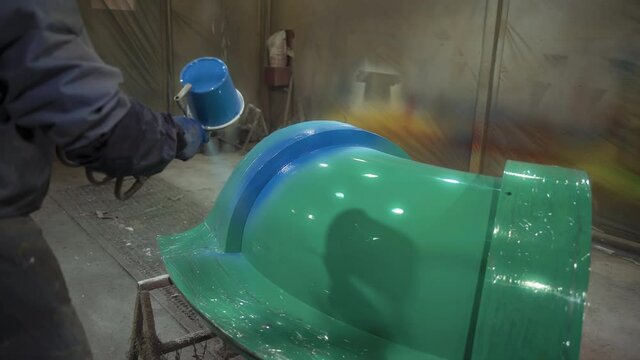 Worker Sprays Paint on Fiberglass Product from Aerosol Gun in the Painting Room