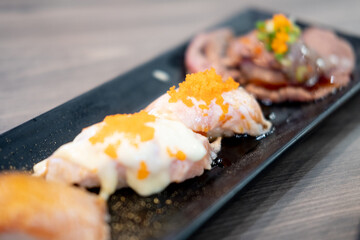 Set of tasty sushi rolls on black tray that looks appetizing.