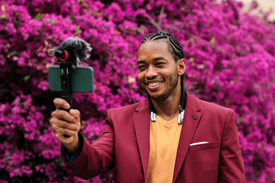 Stylish black blogger recording video on smartphone in garden