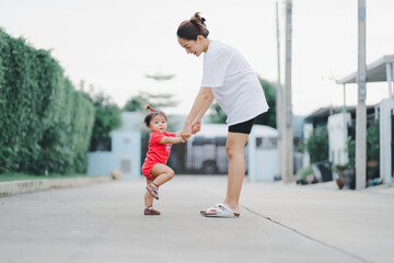 baby step in outdoor to practice balance walk in development according to the age of the child with mother helping daughter support