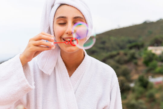 Young female blowing bubbles during skin care routine