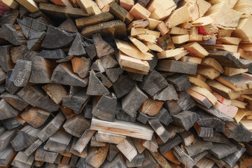 A stack of firewood, stacked chaotically. close-up. Firewood for winter needs for heating a wooden house in the village. Old and new firewood in a raspberry. Texture, side view close-up.