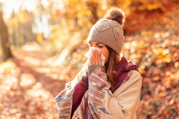 Woman blowing nose on an autumn day