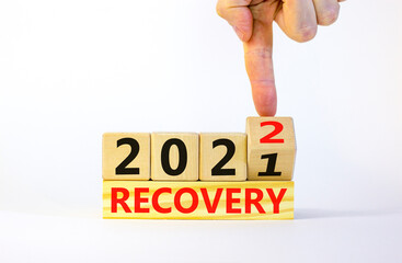 Symbol of planning 2022 recovery new year. Businessman turns a wooden cube and changes words 'recovery 2021' to 'recovery 2022'. Beautiful white background, copy space. Business, 2022 recover concept.