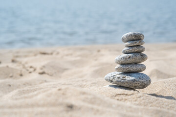 Fototapeta na wymiar Pyramids of gray zen stones on the white sand. Concept of harmony, balance and meditation, spa, massage, relax.