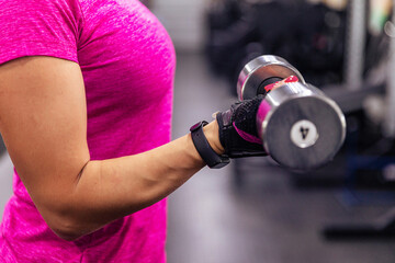 Fototapeta na wymiar Exercise with dumbbells. A woman's hand with dumbbells. Close-up. Gym