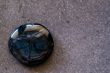 Pierre roulée galet poli en oeil de faucon sur un fond noir - Minéral naturel	