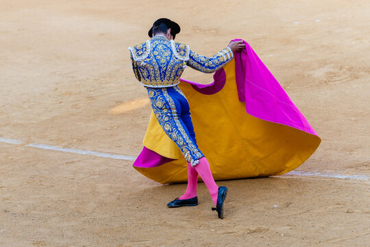 Unrecognizable bullfighter with cape on sandy arena