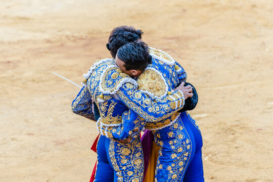 Bullfighters hugging after corrida festival on sandy arena
