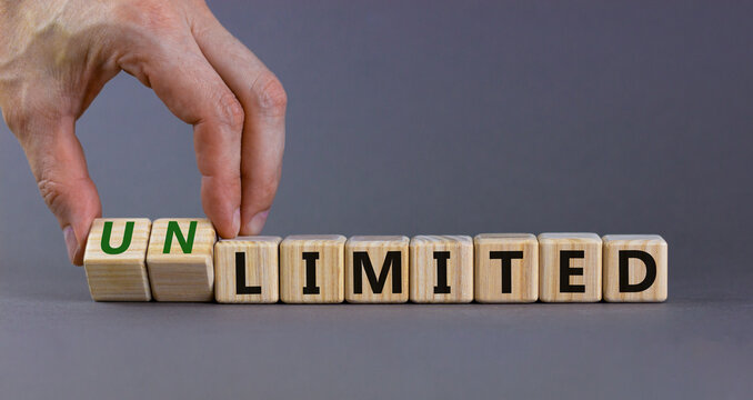 Limited or unlimited symbol. Businessman turns cubes, changes words 'limited' to 'unlimited'. Beautiful grey background, copy space. Business, limited or unlimited concept.