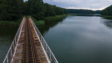 Iron steel frame construction of narrow gauge railway bridge across the river or lake. Bridge with the narrow gauge railway. Aerial view. Space for text.