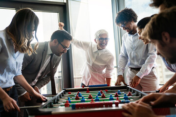 Employees playing table soccer indoor game in the office during break time