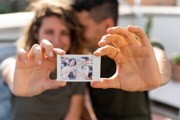 Couple in love holding an instant photo. Horizontal view of young couple together in a relationship.