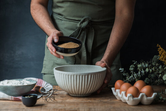 Crop cook adding cane sugar to pastry batter