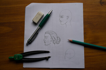 A beginner's drawing of a woman's face. On a wooden table.