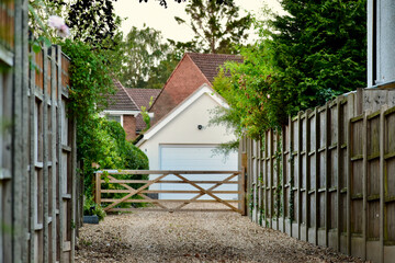Wooden fence and gravel path leading to the garage in the background, England
